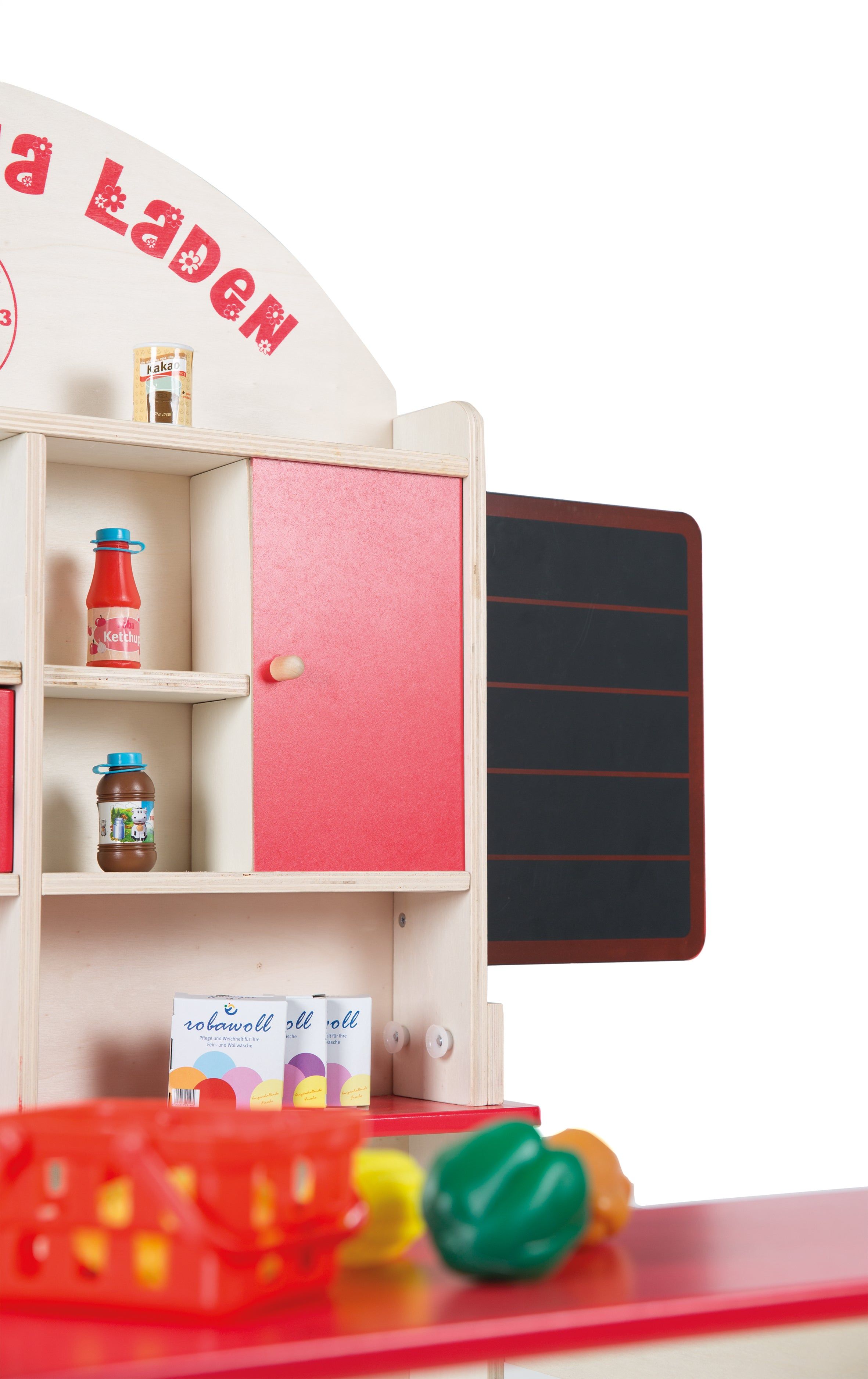 Spielzeug-Verkaufsstand mit Regalen, roter Tür und Tafel. Produkte auf den Regalen. Roter Korb und Gemüse auf der Theke.