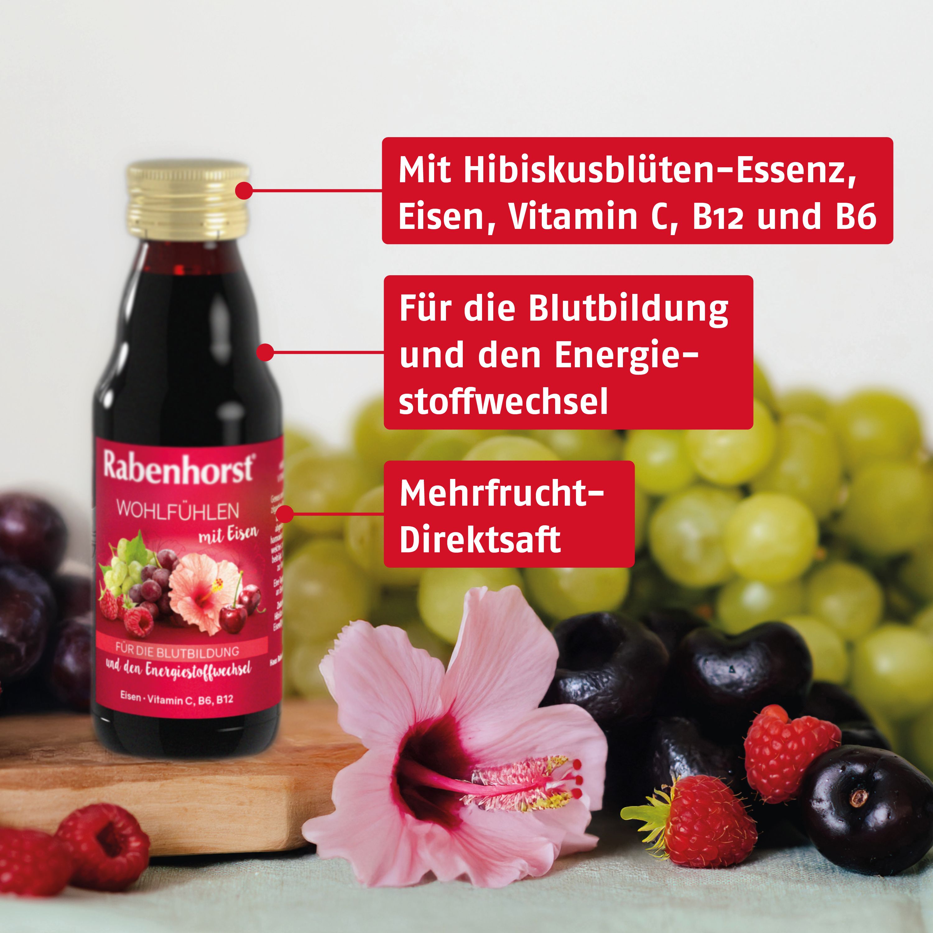 Flasche Rabenhorst Wohlfühlen mit Eisen Saft, umgeben von Früchten und Hibiskusblüten.
