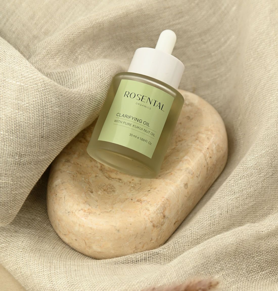 Klarifizierendes Öl auf einem Stein und Stoff. Aufschrift: Rosental Organics, Clarifying Oil, mit Kukui-Nussöl.