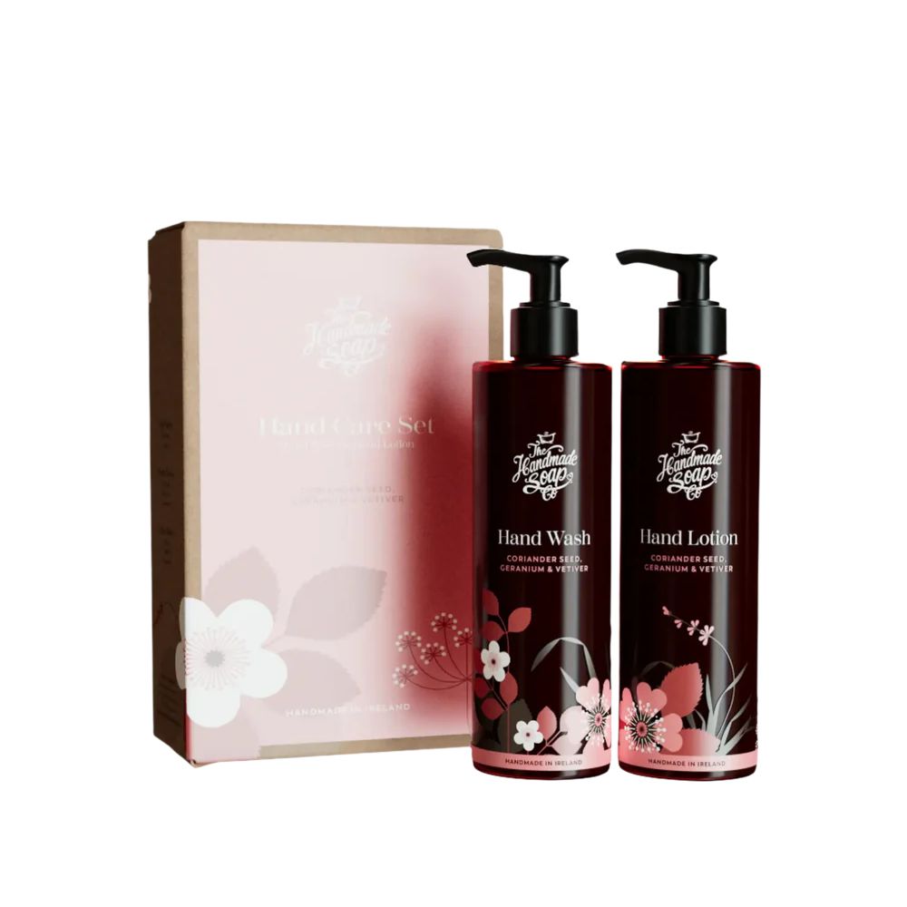 Geschenkset Handseife & Handlotion. Zwei Flaschen mit Pumpaufsatz, dunkelbraun, mit floralem Dekor. Verpackung in rosa Karton.