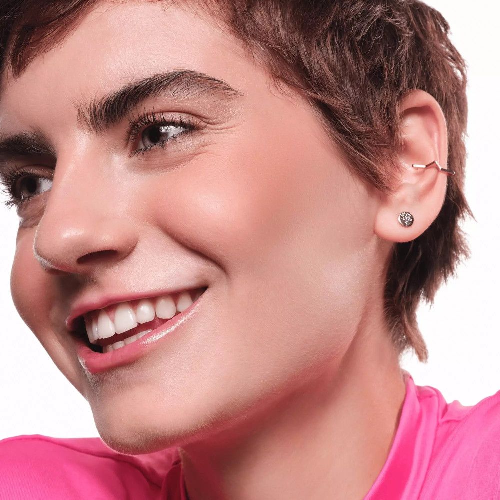 Porträt einer Frau mit gebräunter Haut. Sie lächelt. Deutlich sichtbare Wangenknochen.