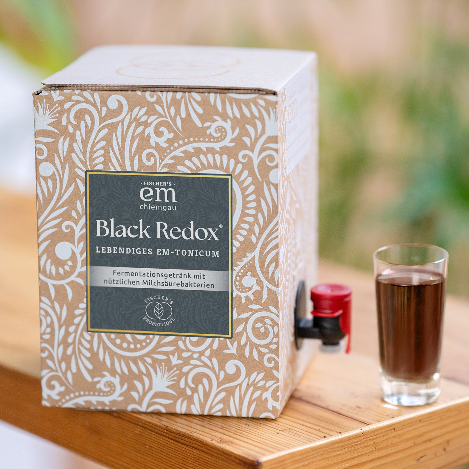 EM-Chiemgau Black Redox Lebendiges EM-Tonicum Fermentgetränk mit Milchsäurebakterien in einem Karton mit Zapfhahn und einem Glas.