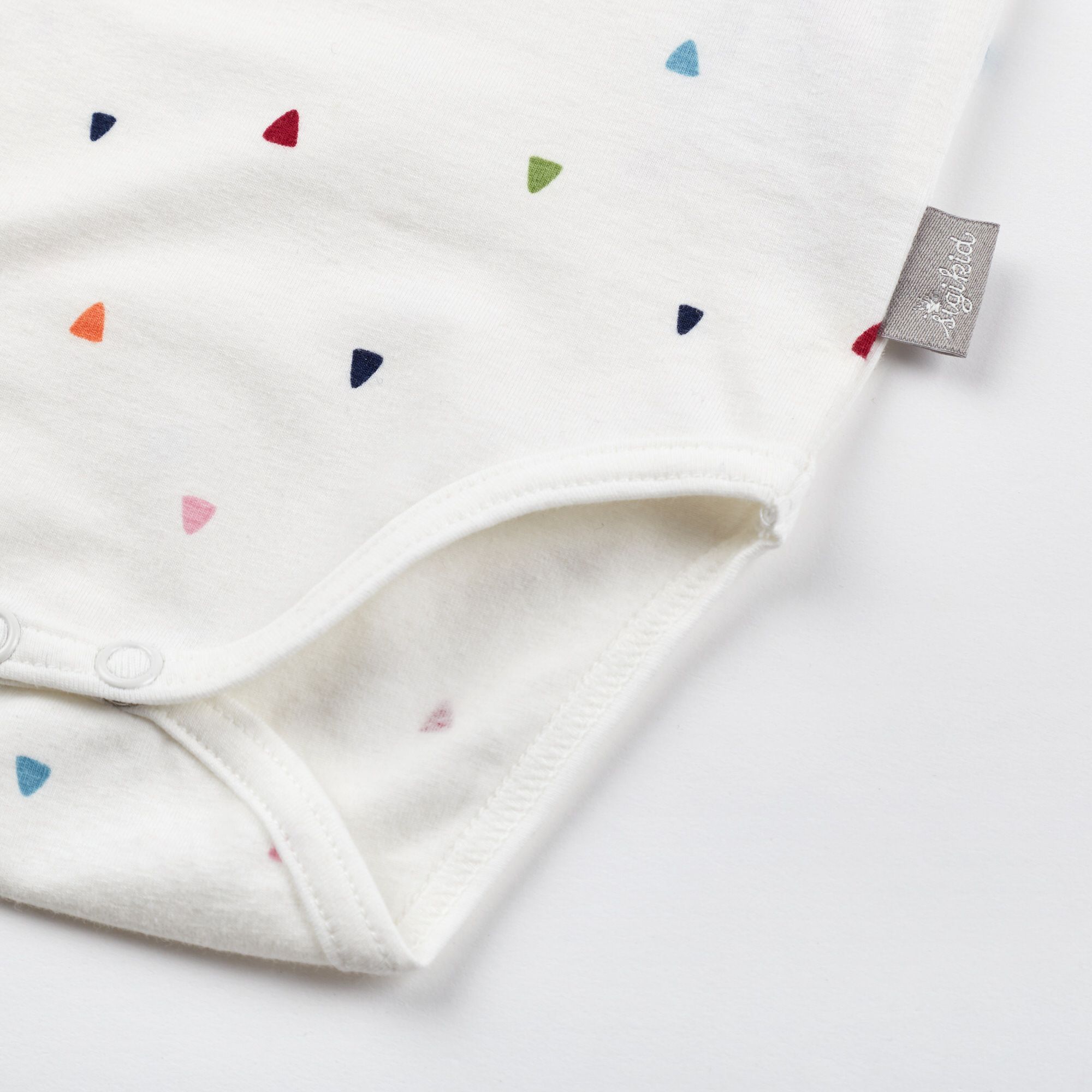 Nahaufnahme des weißen Babybodys. Bunte Dreiecke und Etikett mit Logo.