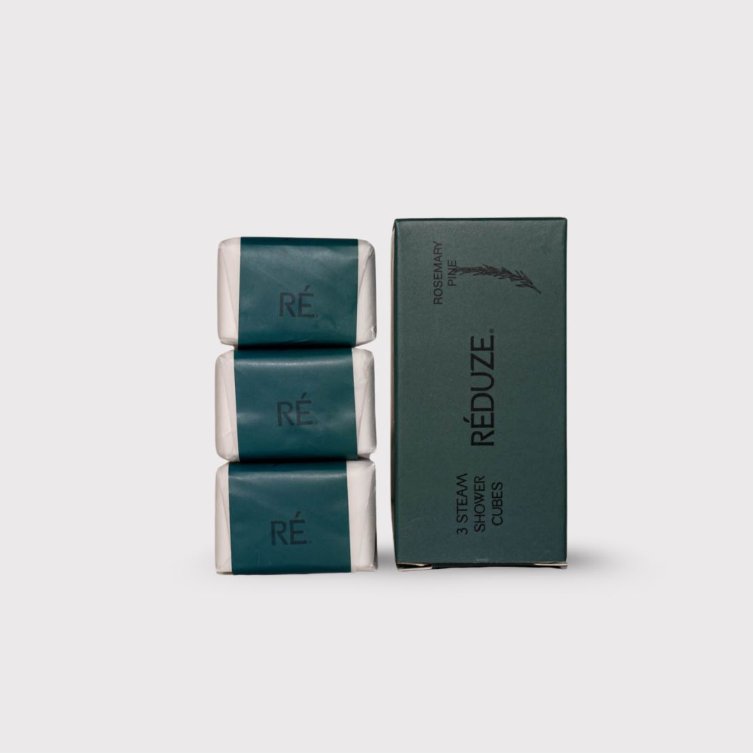 Drei Duschwürfel, verpackt in grünem Papier, neben einer grünen Schachtel mit dem Logo RÉDUZE.