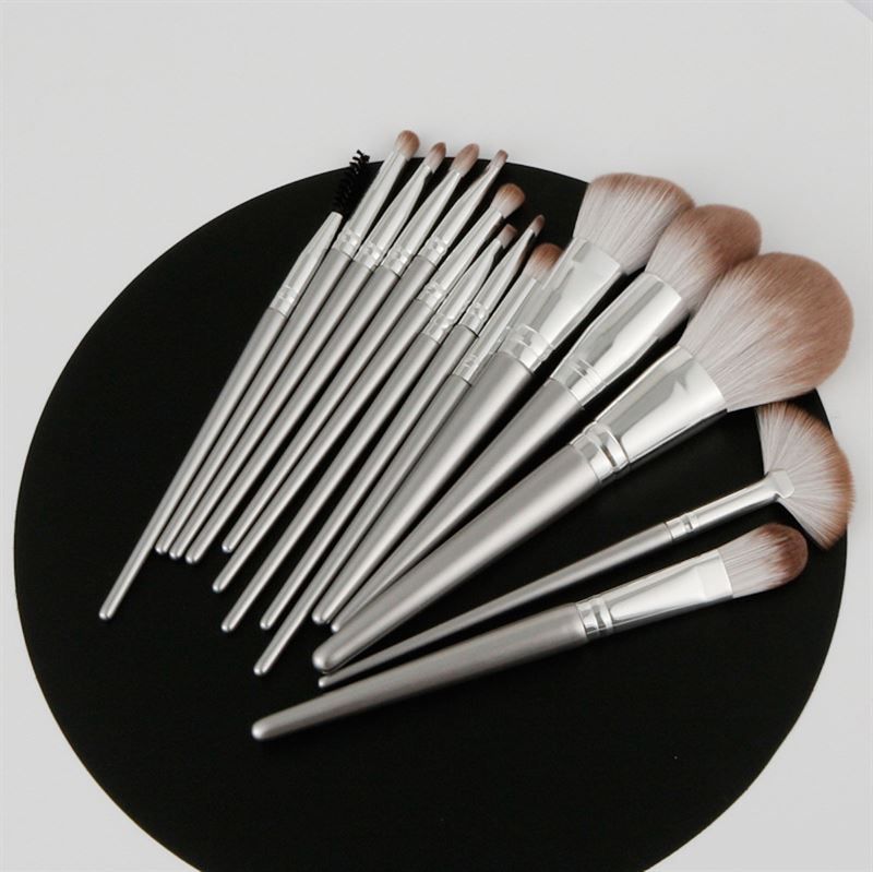 Set von Make-up-Pinseln mit silberfarbenen Griffen und hellbraunen Borsten. Auf schwarzem Untergrund angeordnet.