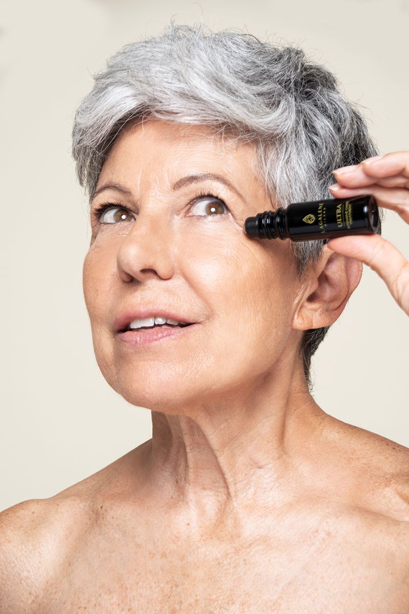 Eine Frau hält eine Lagalene Milano Ultra Intensive Care Flasche mit Roll-on-Applikator an ihr Auge. Auf der Flasche steht "ULTRA INTENSIVE TREATMENT".