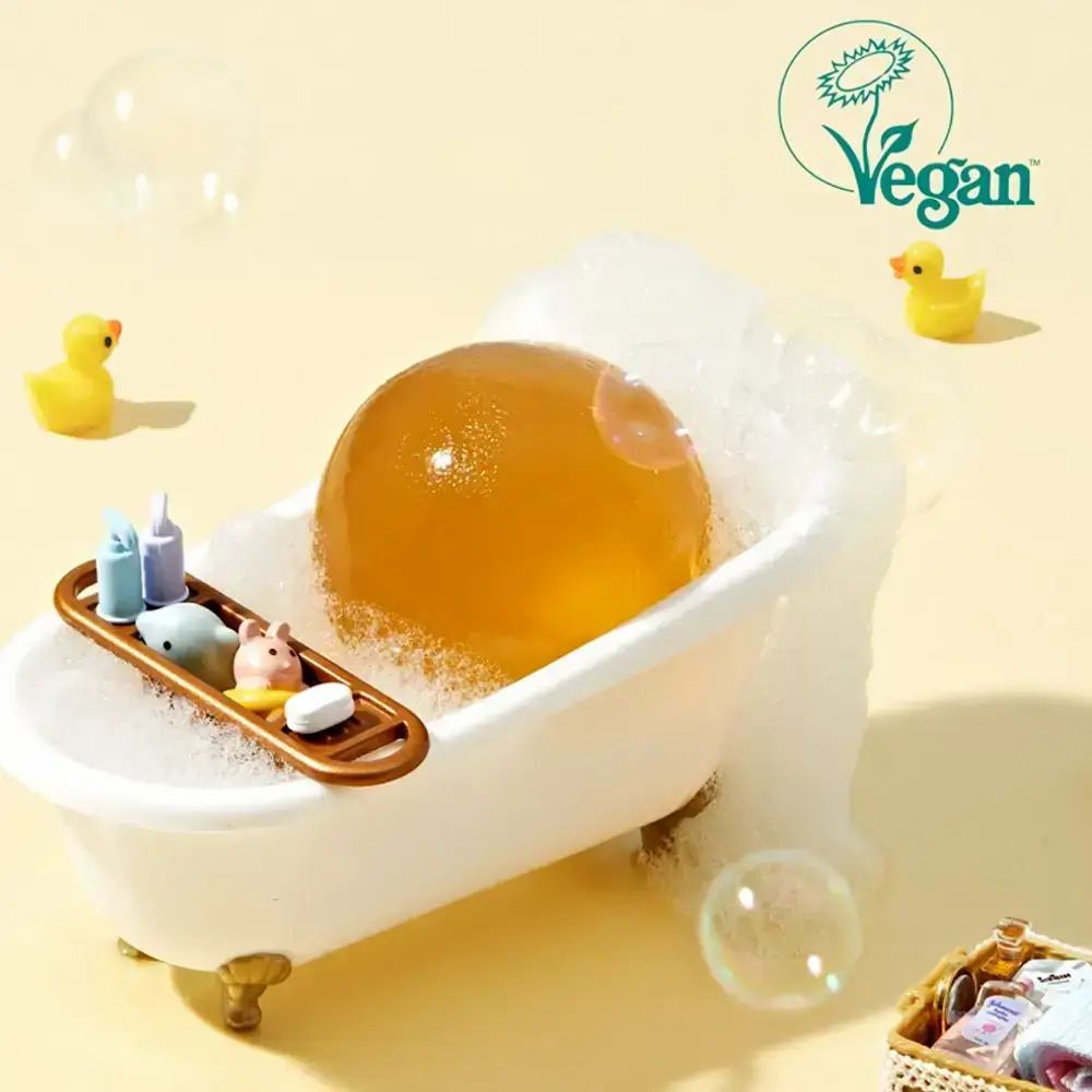 Gelbe Kugel in Miniatur-Badewanne mit Schaum. Vegan-Logo. Enten-Dekorationen.