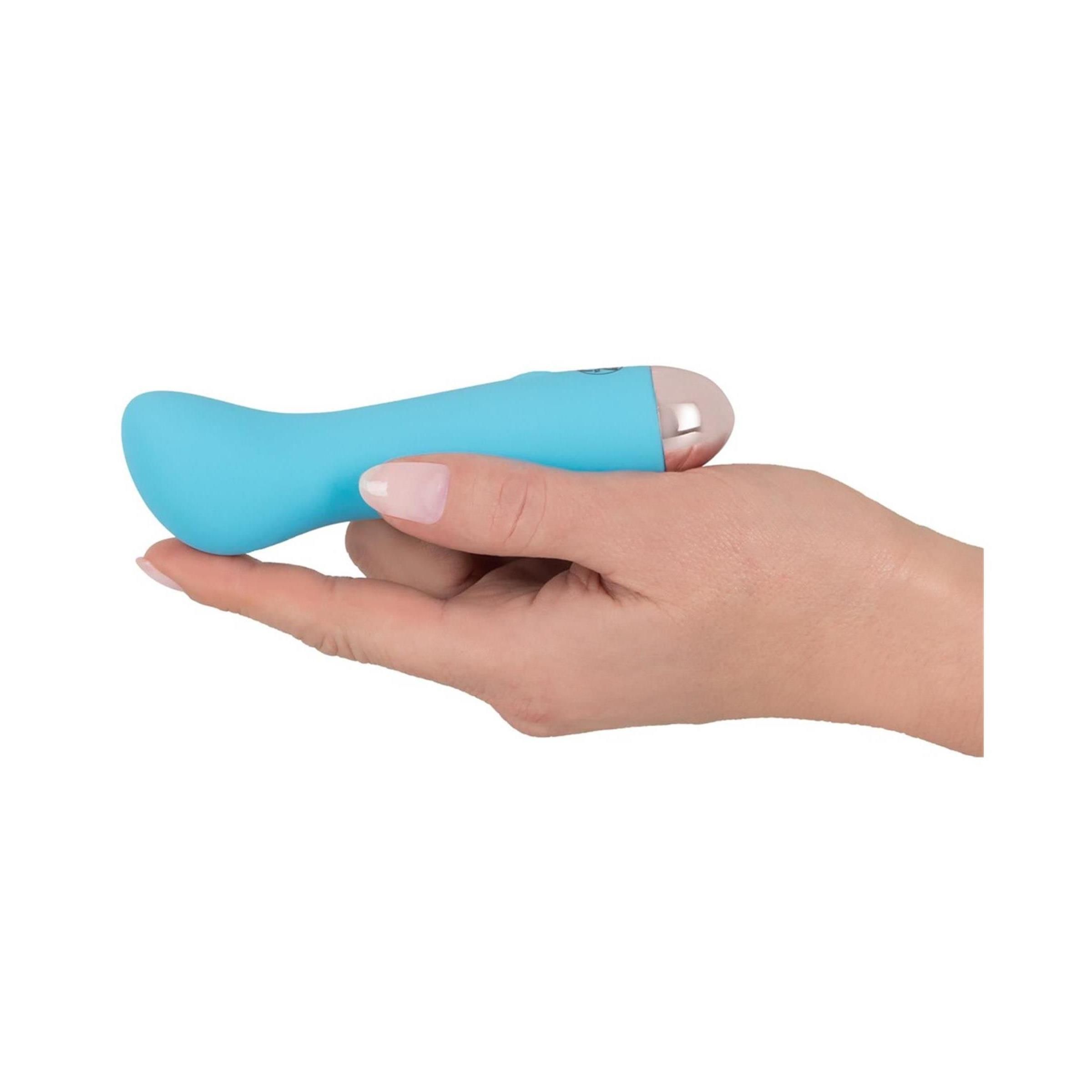 Türkisfarbener Vibrator in einer Hand gehalten. Rosa Spitze.