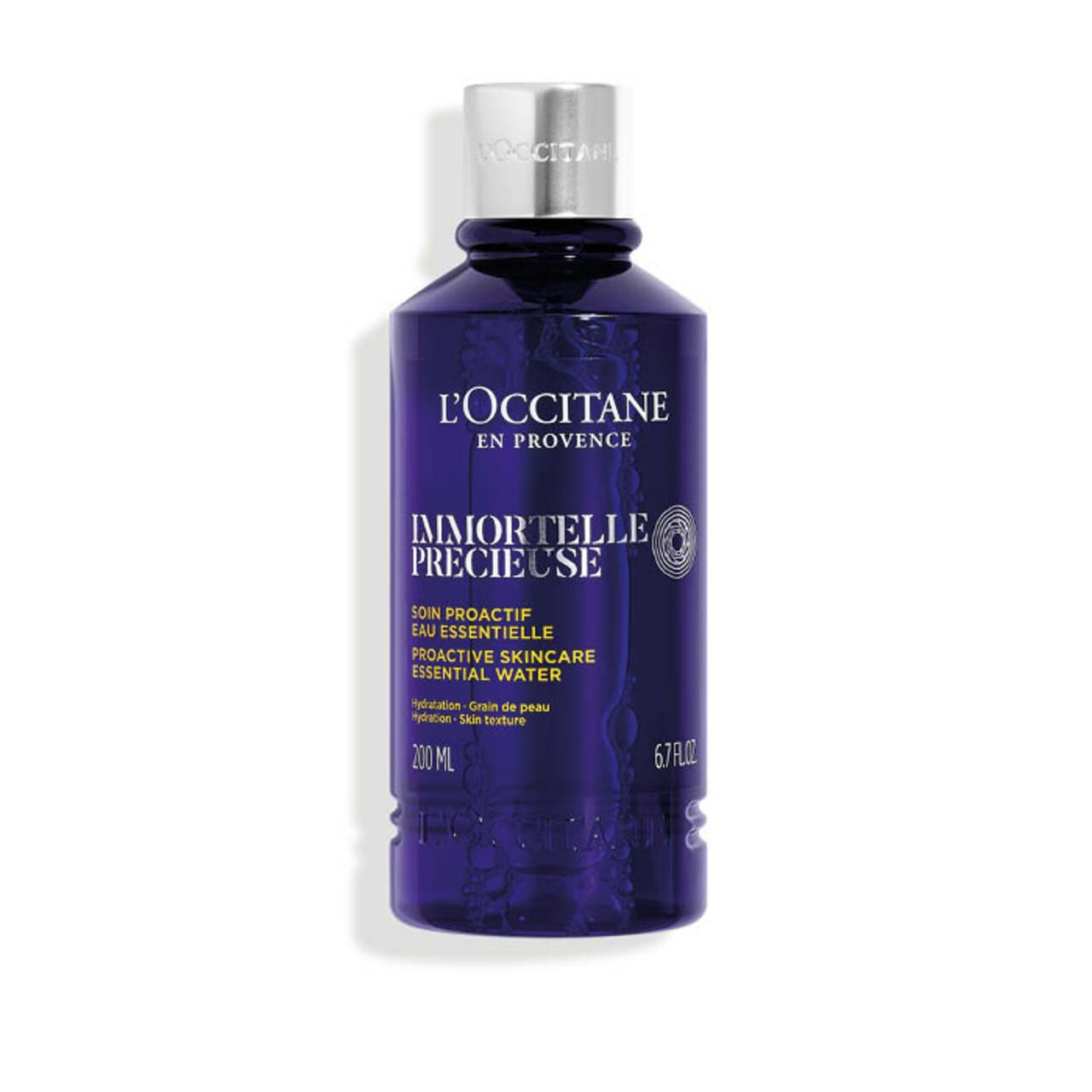 Blau-transparente Flasche mit silbernem Deckel. Aufschrift: L'Occitane, Immortelle Précieuse, 200 ml, 6.7 FL.OZ.