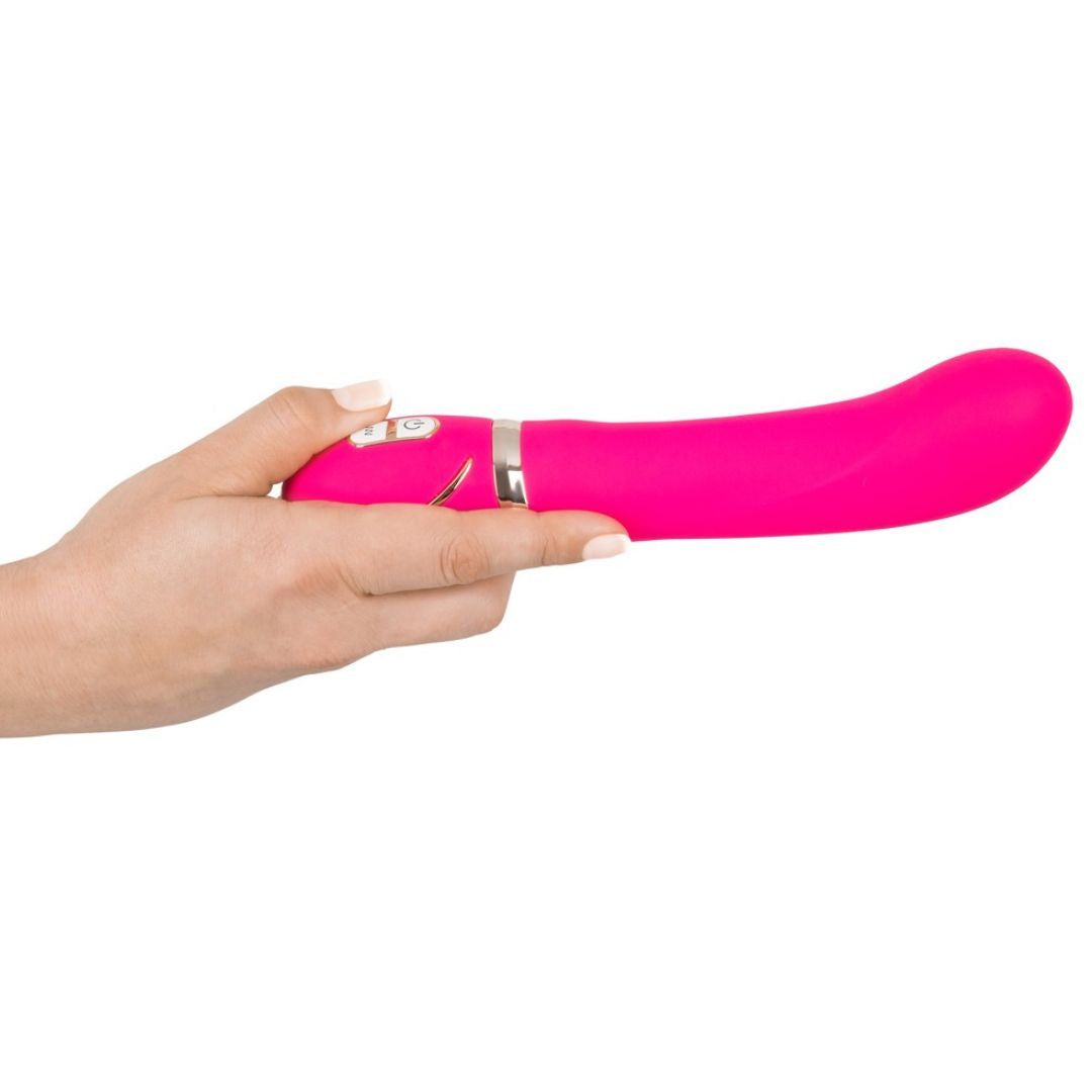 Pinkfarbener Vibrator in einer Hand gehalten. Gebogene Form, silberfarbene Akzente. Zwei Knöpfe.