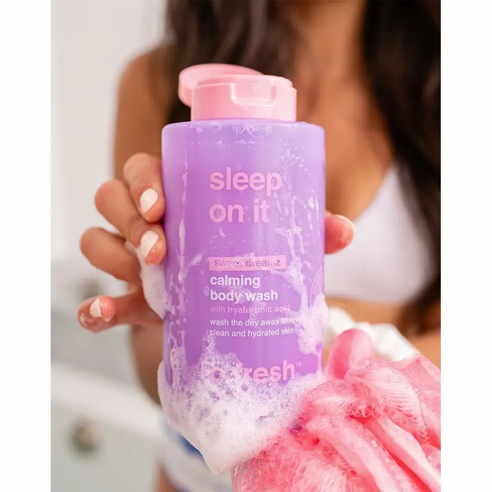 Person hält lila Flasche mit rosa Deckel. Text: Sleep On It, Calming Body Wash, b.fresh. Schaum auf Flasche.