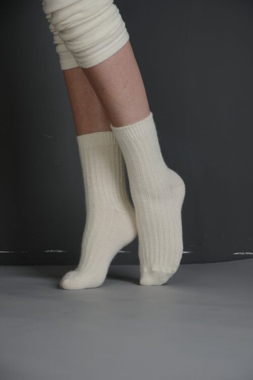 Beige Socken mit geripptem Muster. Füße und Beinbekleidung auf grauem Untergrund.