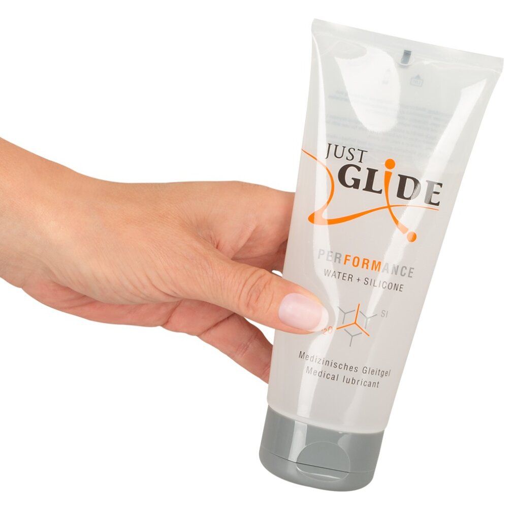 Hand hält Tube. Aufschrift: Just Glide Performance, Wasser + Silikon. Grauer Verschluss.