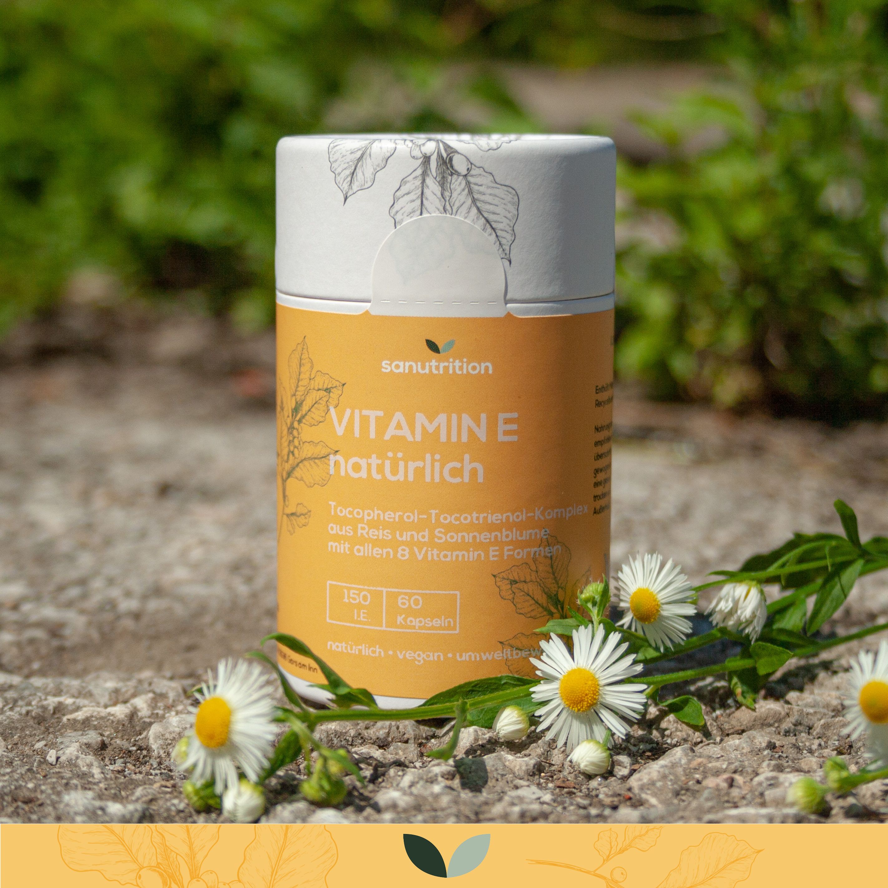 Zylinderförmige Dose mit Sanutrition Vitamin E. Aufschrift: Vitamin E natürlich. Mit Kamillenblüten dekoriert.
