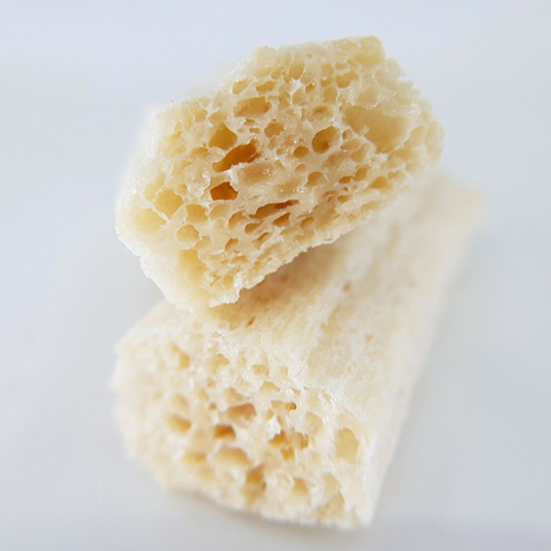 Nahaufnahme von zwei Puffed Crackern. Die Oberfläche ist uneben und weist eine helle, beige Farbe auf.