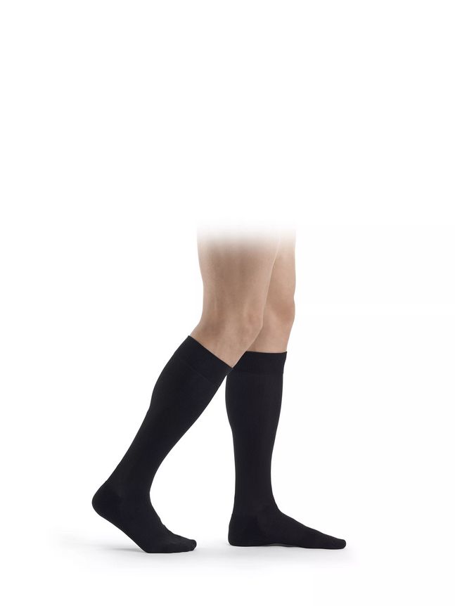 Schwarze Kompressionsstrümpfe am Bein einer Person. Sichtbar sind die Strümpfe bis zum Knie.