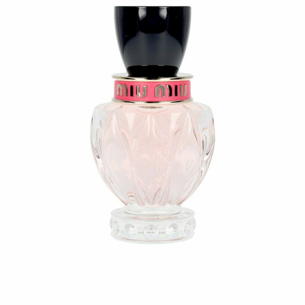 Parfümflakon mit rosa Flüssigkeit. Schwarzer Deckel, rosa und silberfarbener Ring mit Schriftzug. Klarer, geriffelter Glasbehälter.