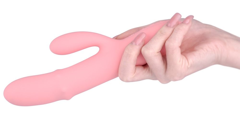 Rosa Vibrator in Hand gehalten. Längliche Form mit gebogenem Teil. Glatte Oberfläche.