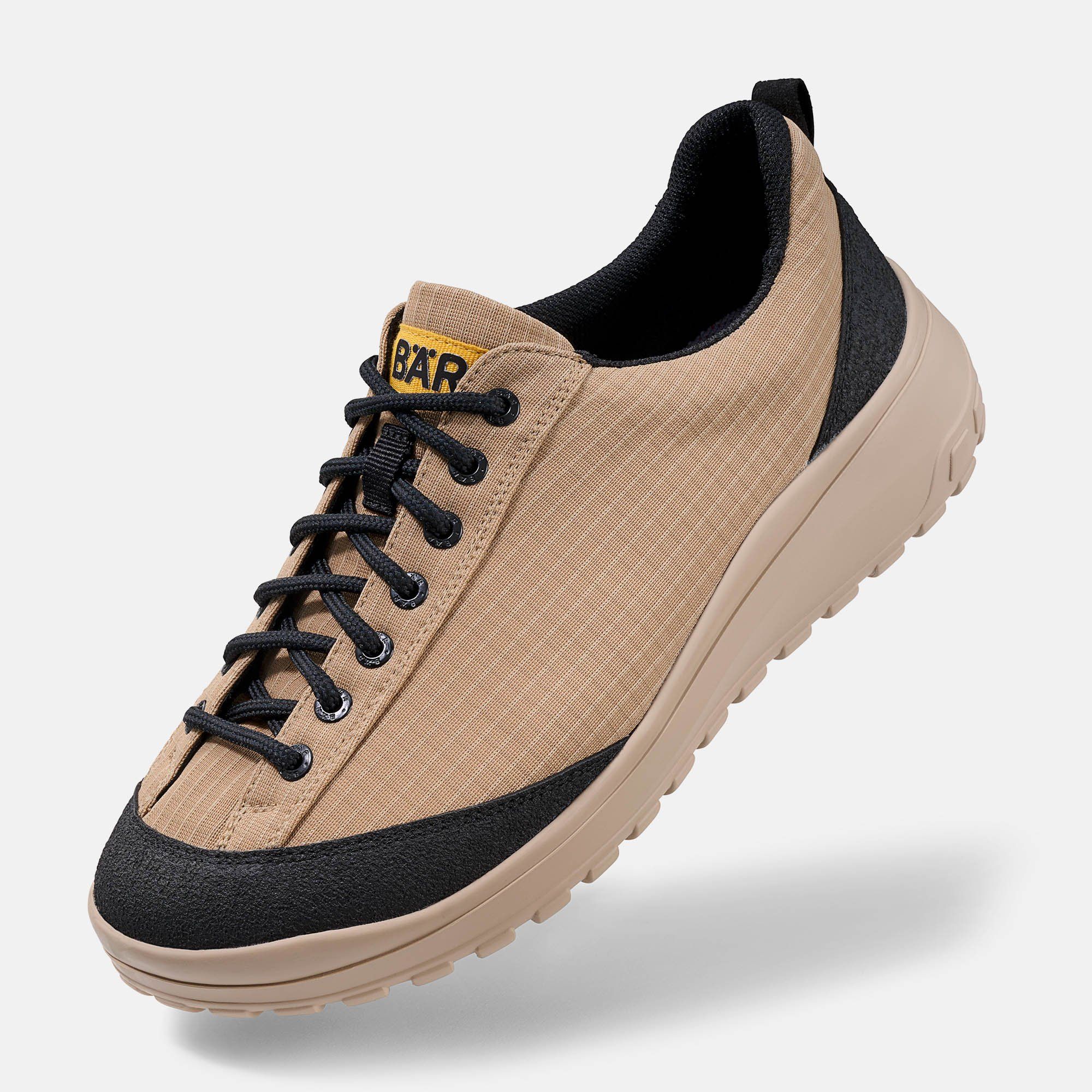 Beige Schnürschuh mit schwarzem Rand und Schnürsenkeln. Gelbes Logo "BÄR".