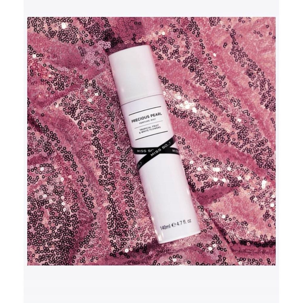 Weiße zylindrische Flasche. Etikett: Precious Pearl, Tropical Fruit & White Flowers. Schwarzes Band mit Miss So. Auf rosa Paillettenstoff.