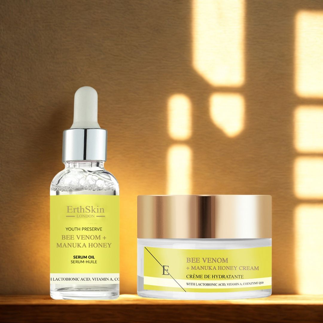 Serumflasche und Cremebehälter. Beide mit gelben Etiketten und Produktnamen. Serum mit Pipette. Creme mit goldenem Deckel, auf Holz.