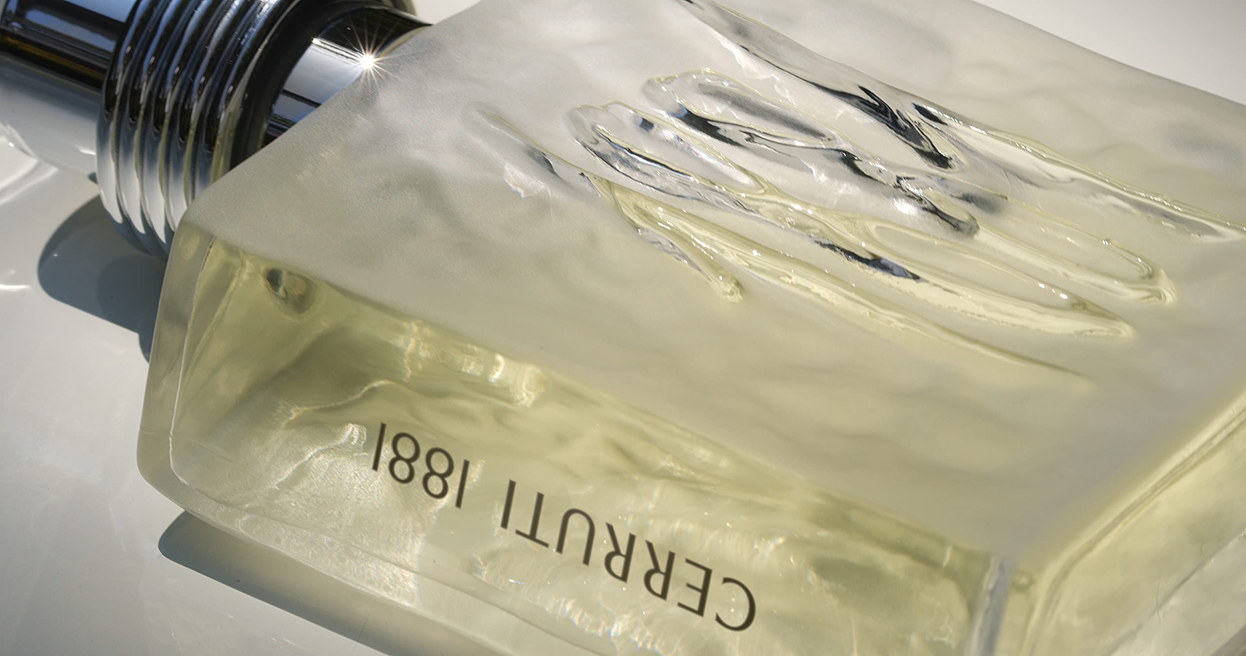 Nahaufnahme eines Flakons. Auf der Vorderseite ist die Zahl 1881 eingeprägt. Der Flakon ist mit einer gelblichen Flüssigkeit gefüllt. Der Name Cerruti 1881 ist sichtbar.