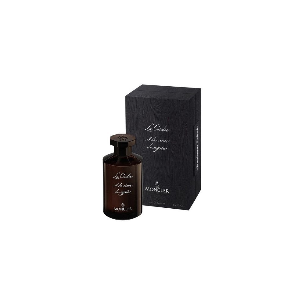 Braune Glasflasche mit dunklem Etikett und achteckigem Verschluss, daneben schwarze Verpackungsbox mit Schriftzug und Moncler-Logo.