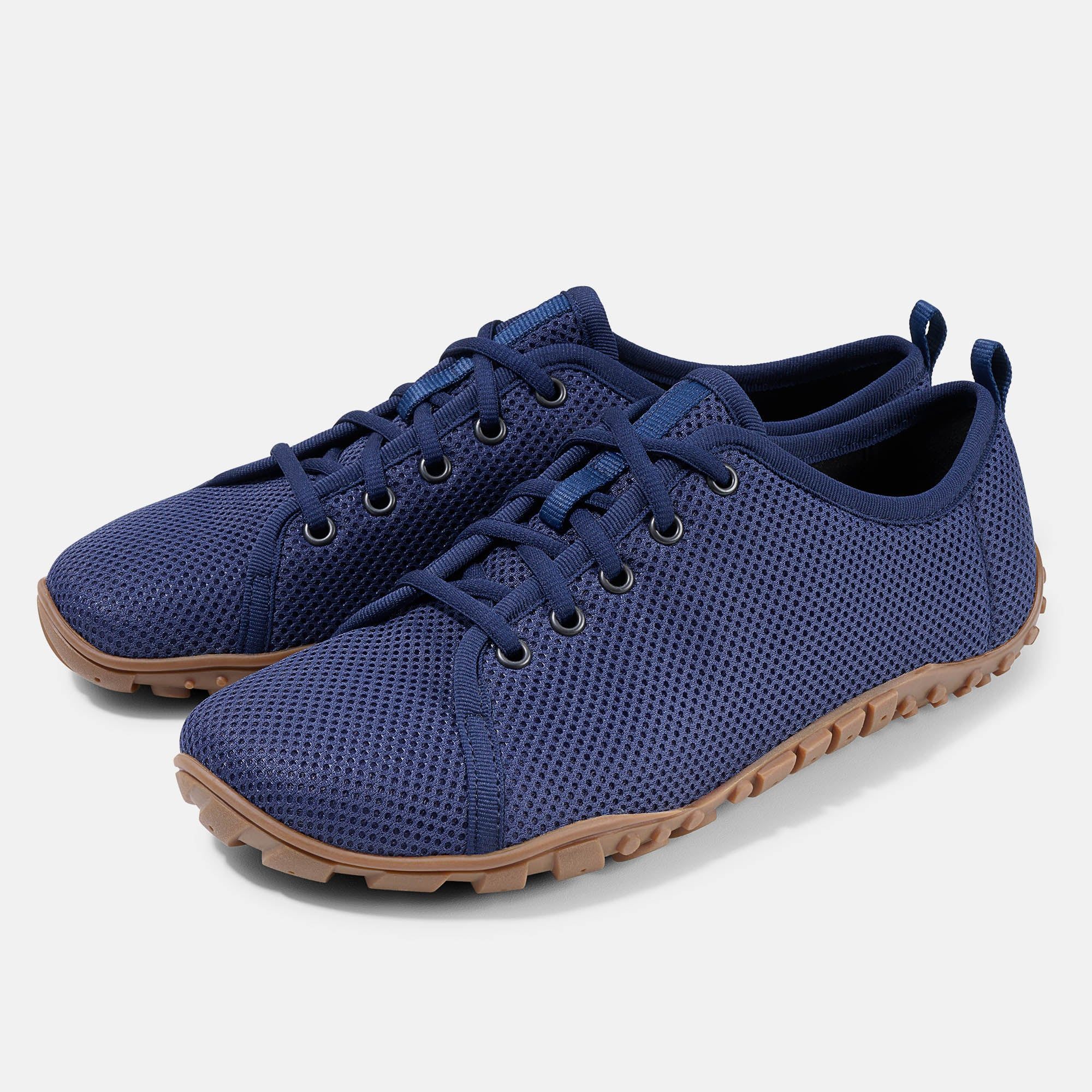 Zwei blaue Schnürschuhe mit brauner Sohle. Mesh-Obermaterial, Schnürsenkel, Ösen und Zuglasche. Breite Passform.