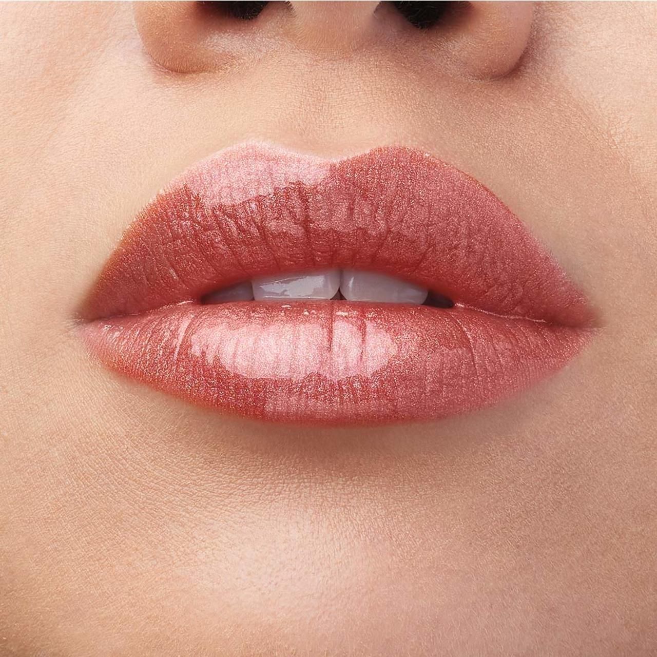 Nahaufnahme von Lippen mit Lip Lacquer. Glänzender, rosafarbener Farbton. Haut im Hintergrund.
