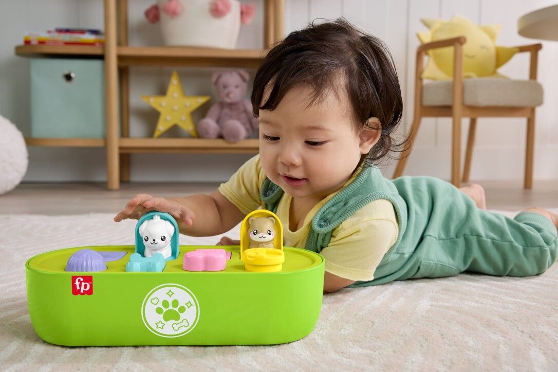 Baby spielt mit Pop-up-Spielzeug. Grünes Spielzeug mit Tierfiguren und bunten Knöpfen.