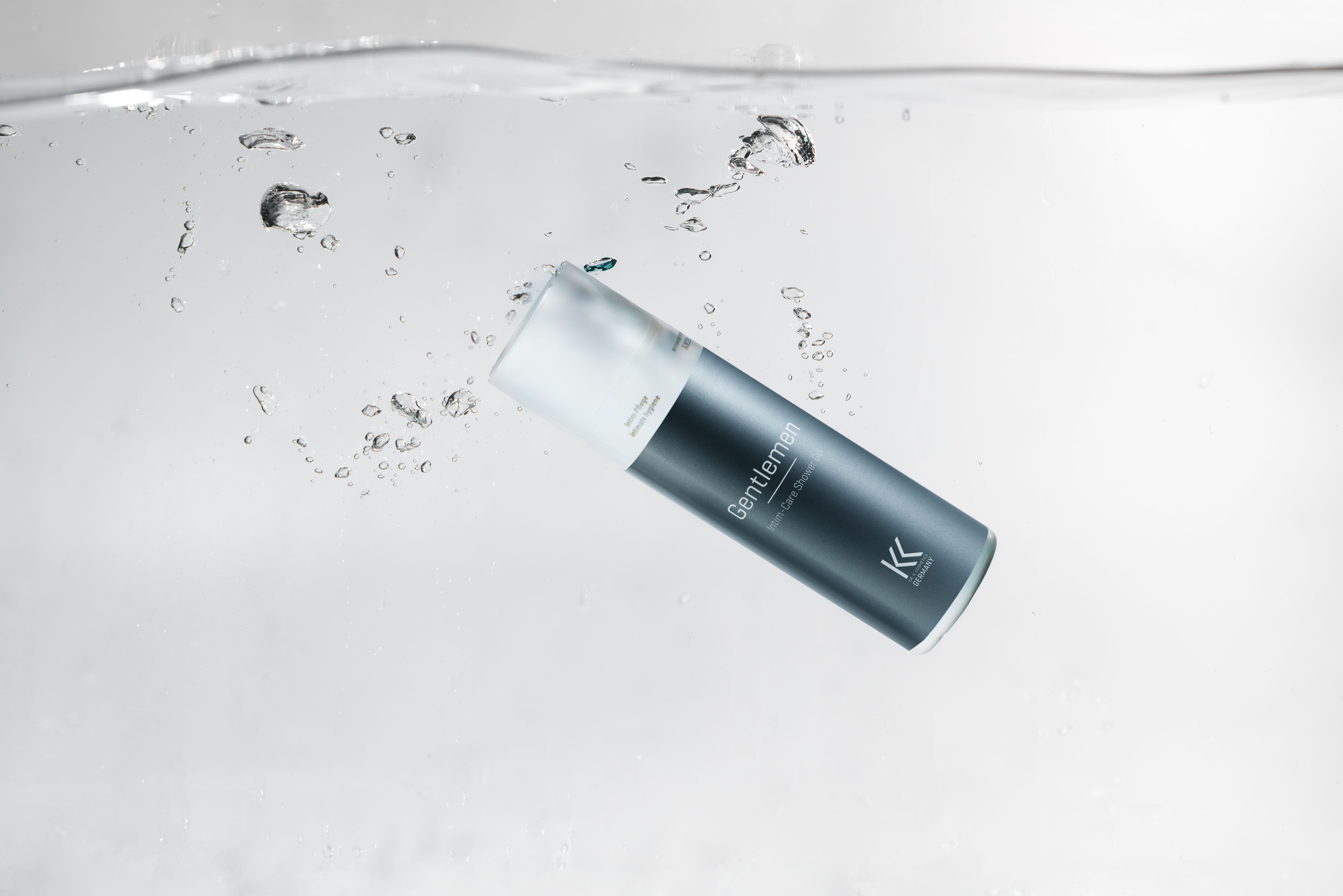 Intim-Duschgel im Wasser. Produktname: Gentlemen Intim-Care Shower Gel. Schwarze Flasche mit weißem Deckel. Wasser mit Blasen.