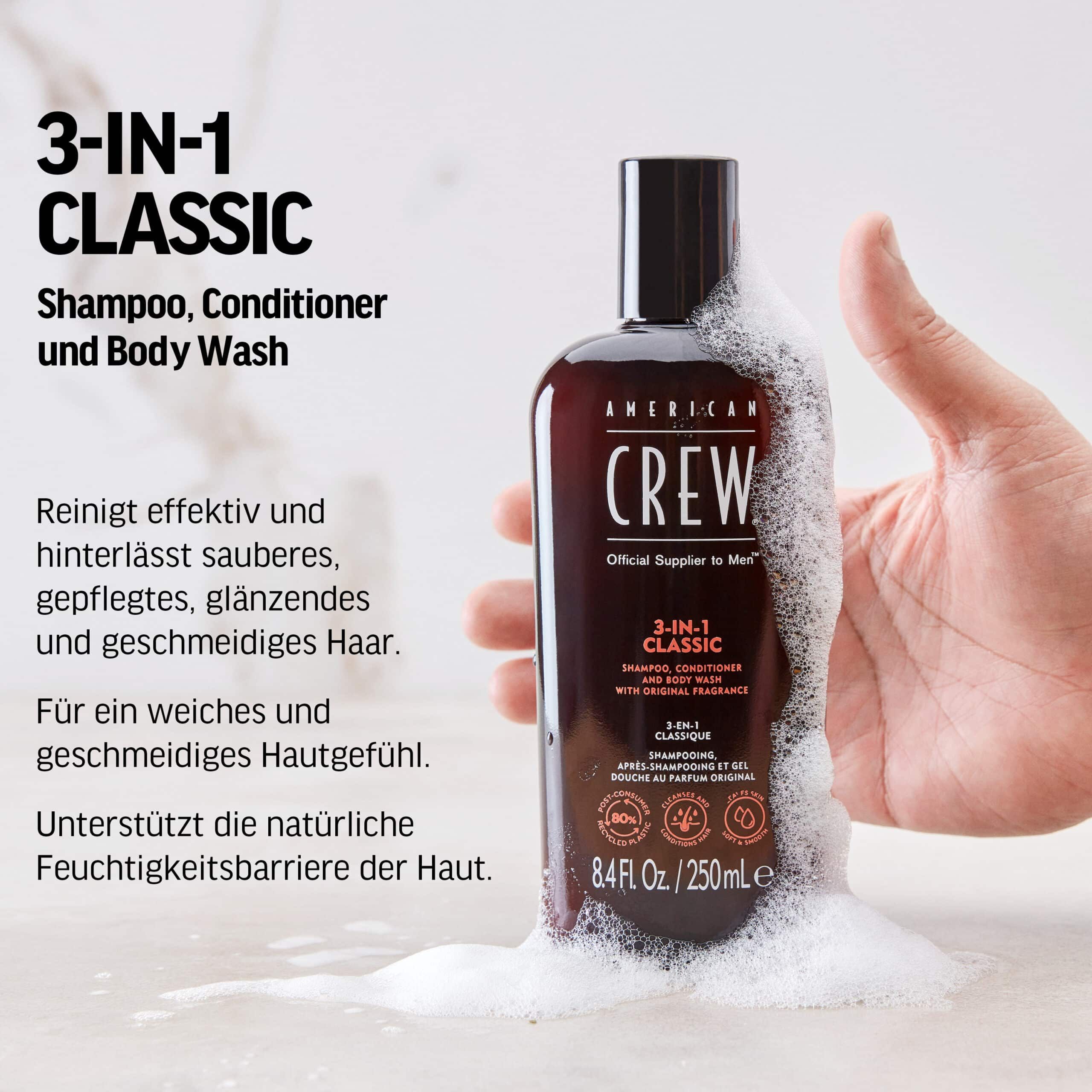 Braune Flasche mit schwarzem Deckel. Produktname: AMERICAN CREW 3-in-1 Classic. Schaum umgibt die Flasche. Hand hält die Flasche.