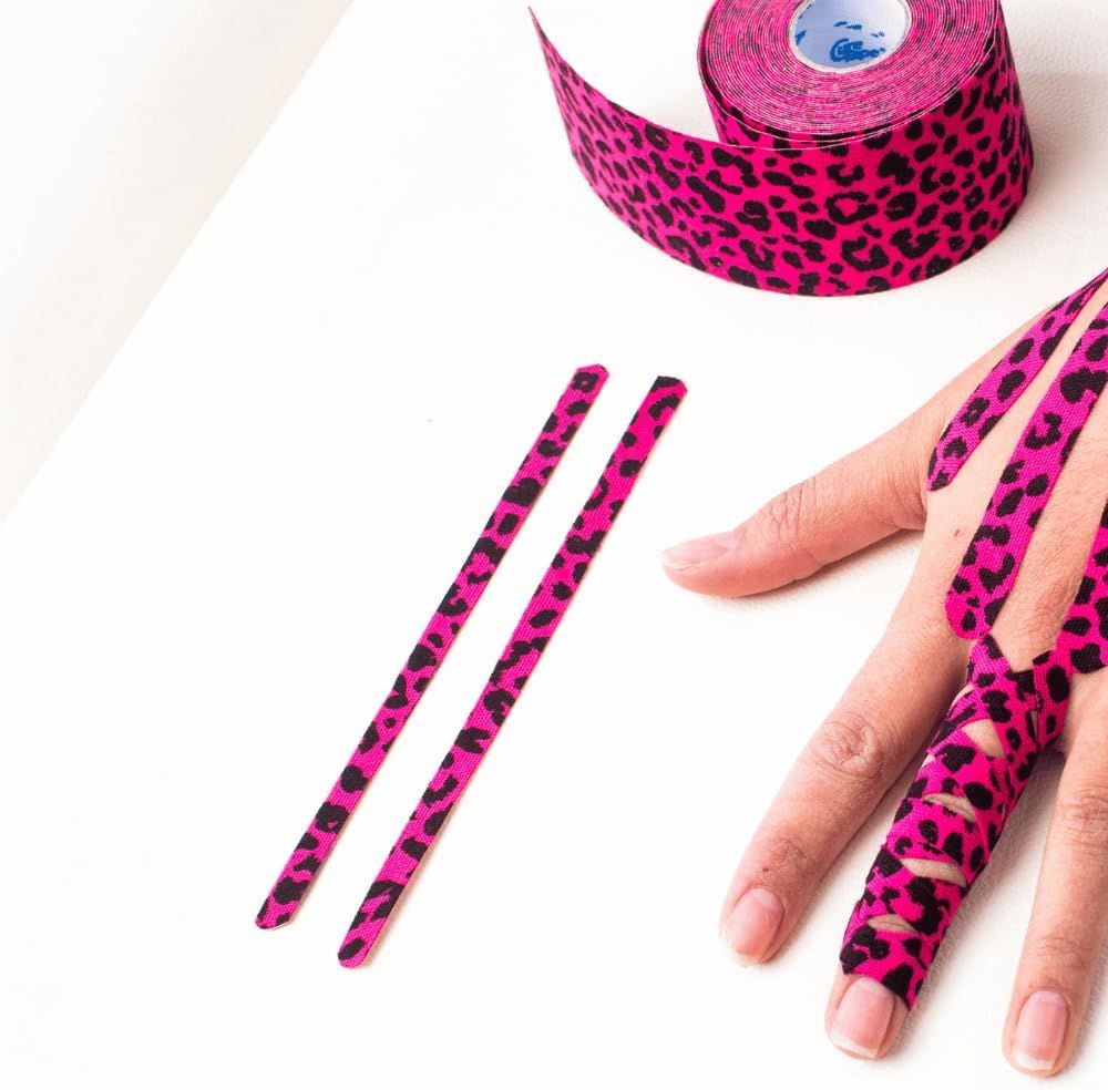 Pinker Kinesiotape mit Leopardenmuster auf Fingern und einer Rolle. Zwei geschnittene Streifen liegen daneben.