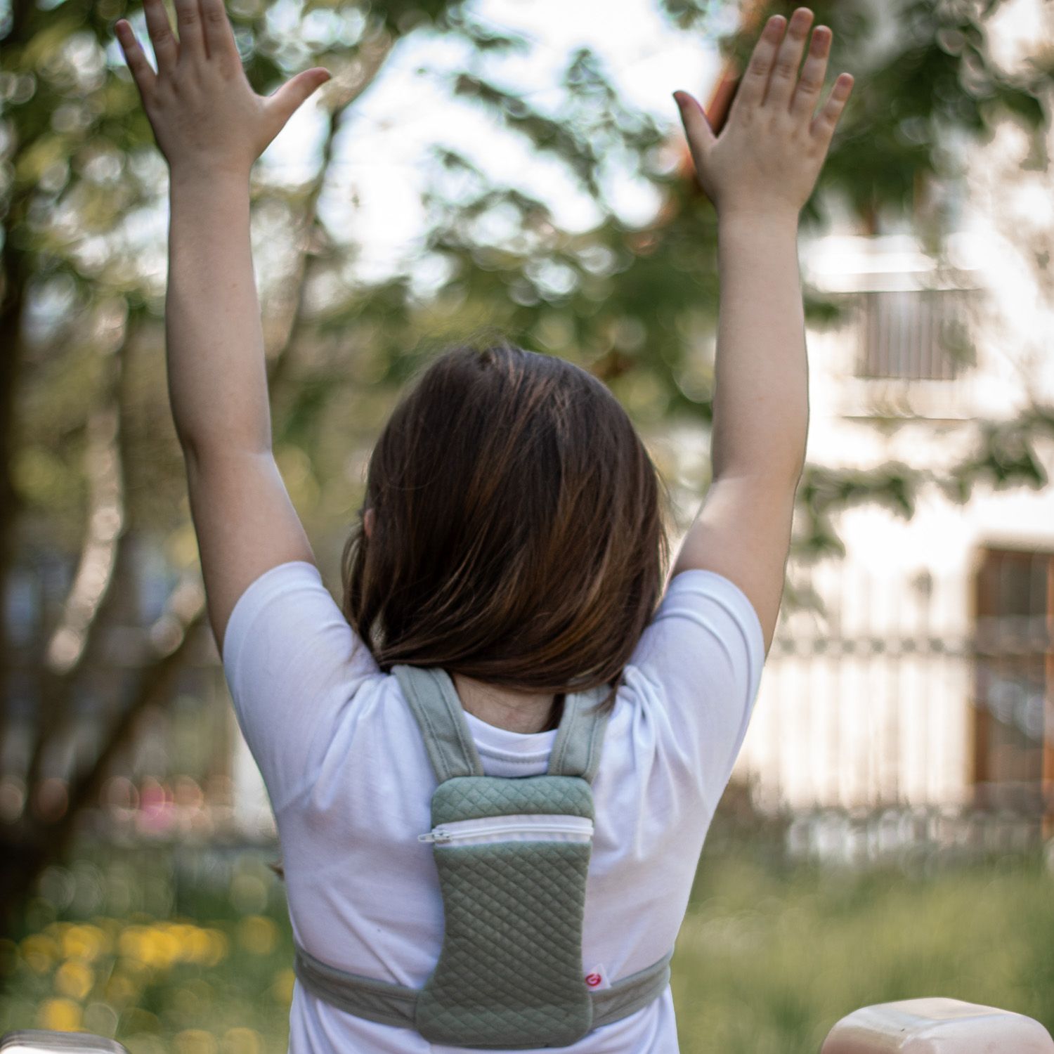 Kind mit grünem Rucksack auf dem Rücken. Arme nach oben gestreckt. Gestepptes Muster.