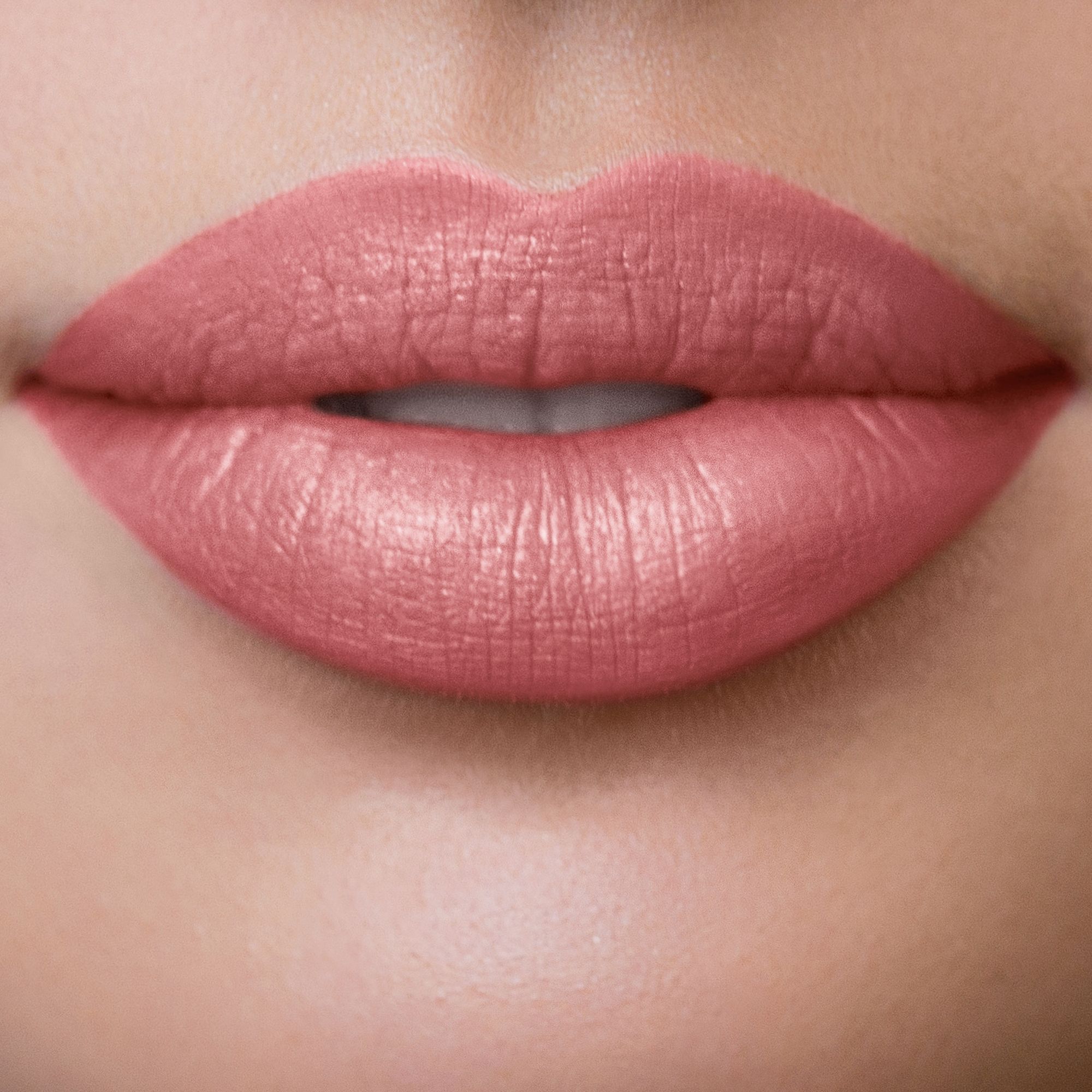 Nahaufnahme von Lippen, die mit rosa Lippenstift geschminkt sind. Die Lippen sind glatt und glänzend.