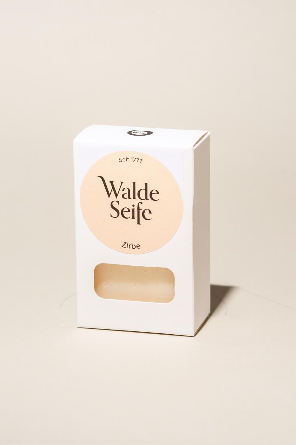 Weiße Verpackung mit rundem Etikett. Darauf steht "Walde Seife Zirbe". Ein rechteckiges Fenster zeigt die Seife.