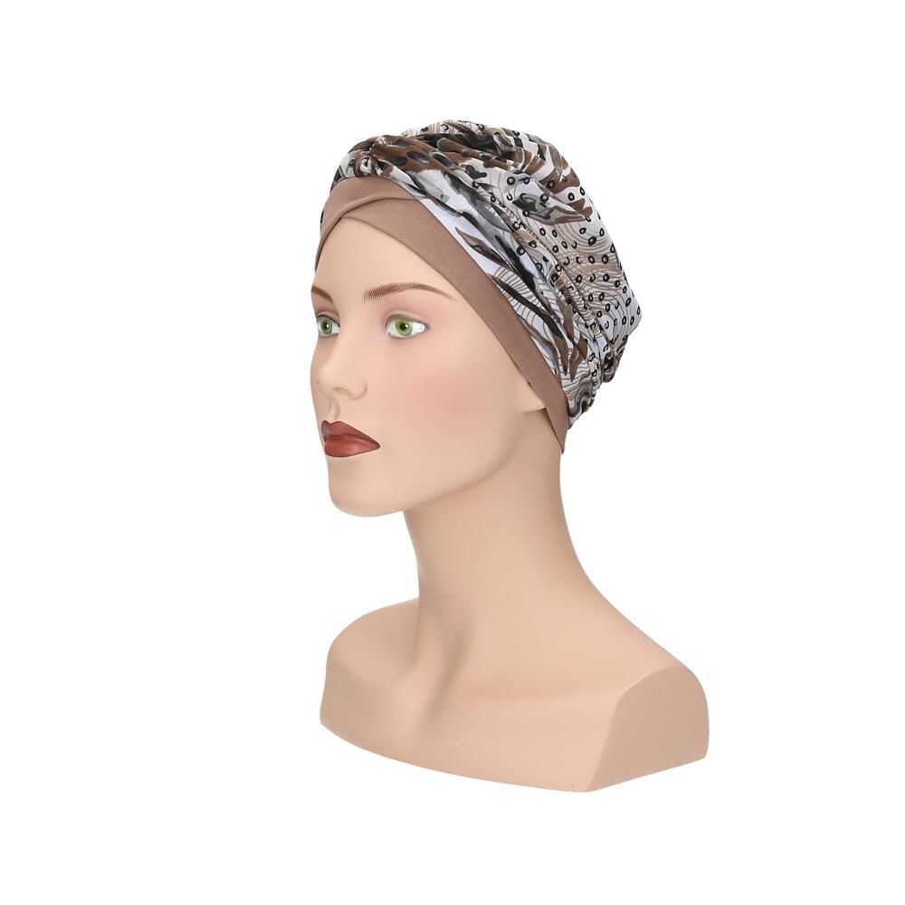 Turban mit Muster auf einer Schaufensterpuppe. Beige Grundfarbe, gemusterter Stoff in Braun- und Beigetönen. Seitenansicht.