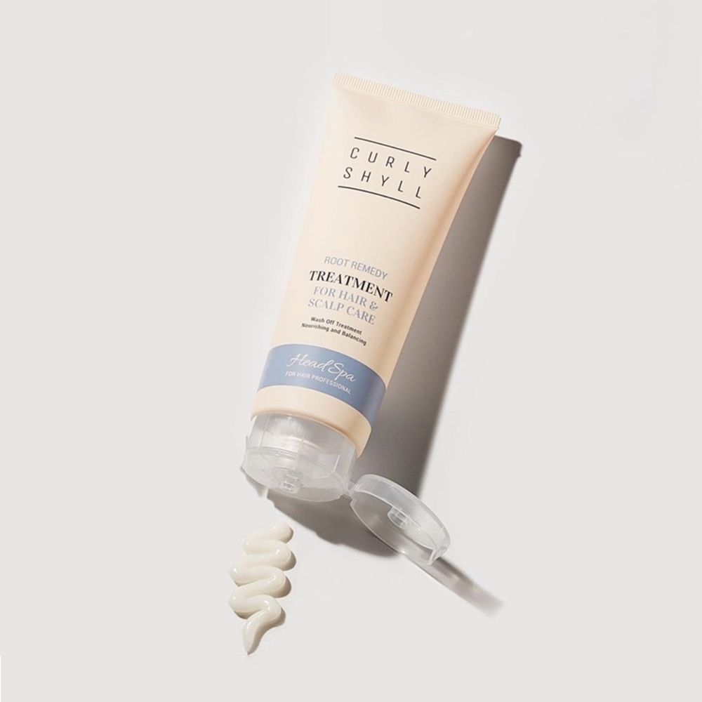 Beige Tube mit Produkttext. Aufschrift: CURLY SHYLL, Root Remedy Treatment, für Haar & Kopfhautpflege. Blaue Leiste: Head Spa. Produkt wird herausgedrückt.