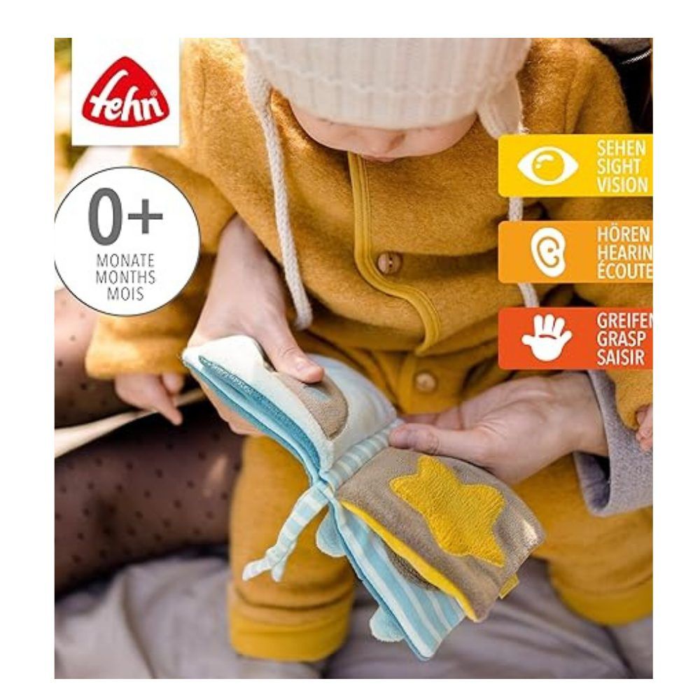 Baby hält Stoffbuch mit Stern-Motiv. Marke: fehn. Altersempfehlung: 0+. Mit Symbolen für Sehen, Hören und Greifen.