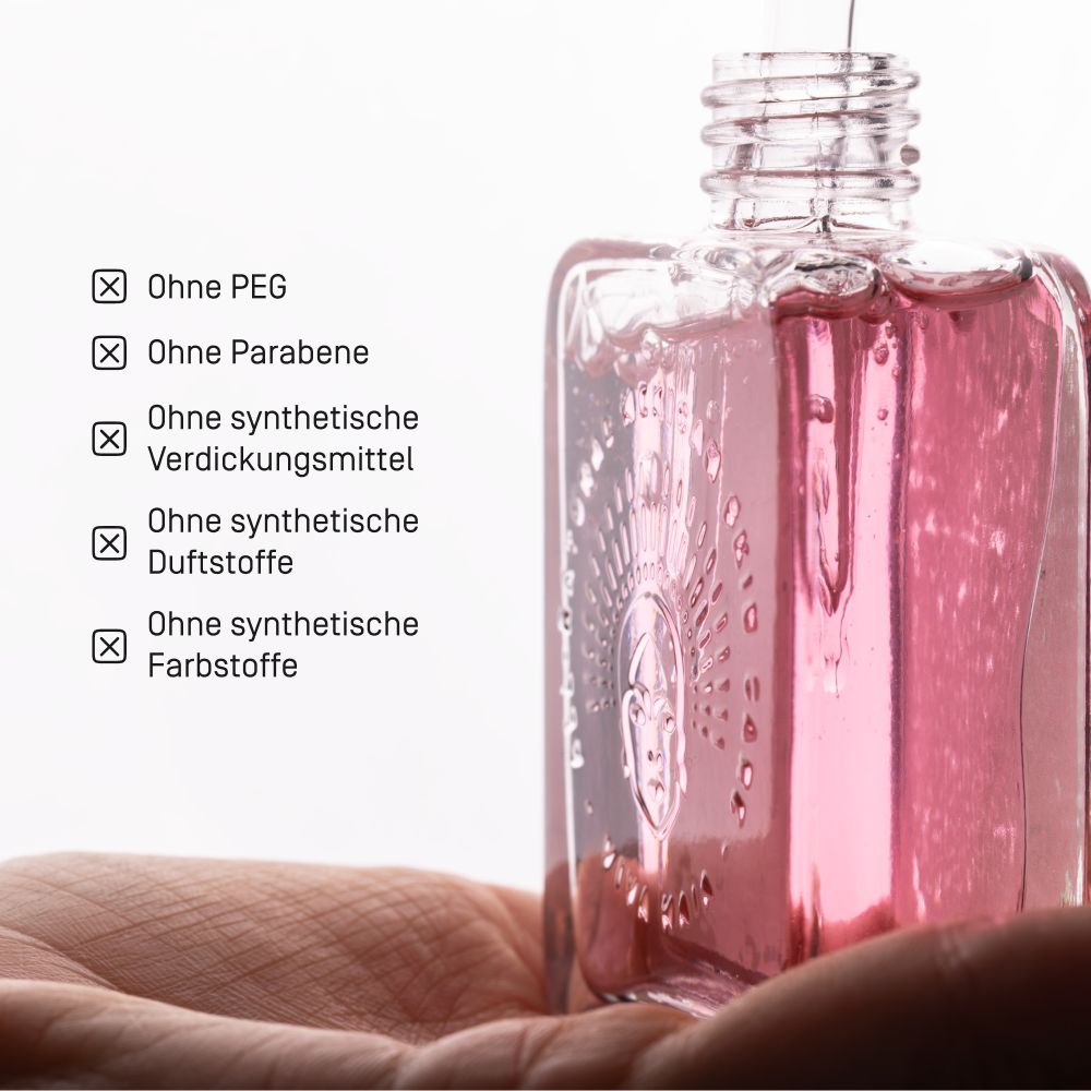 Glasflasche mit rosa Serum und Pipette, gehalten in einer Hand. Text listet "Ohne PEG", "Ohne Parabene".