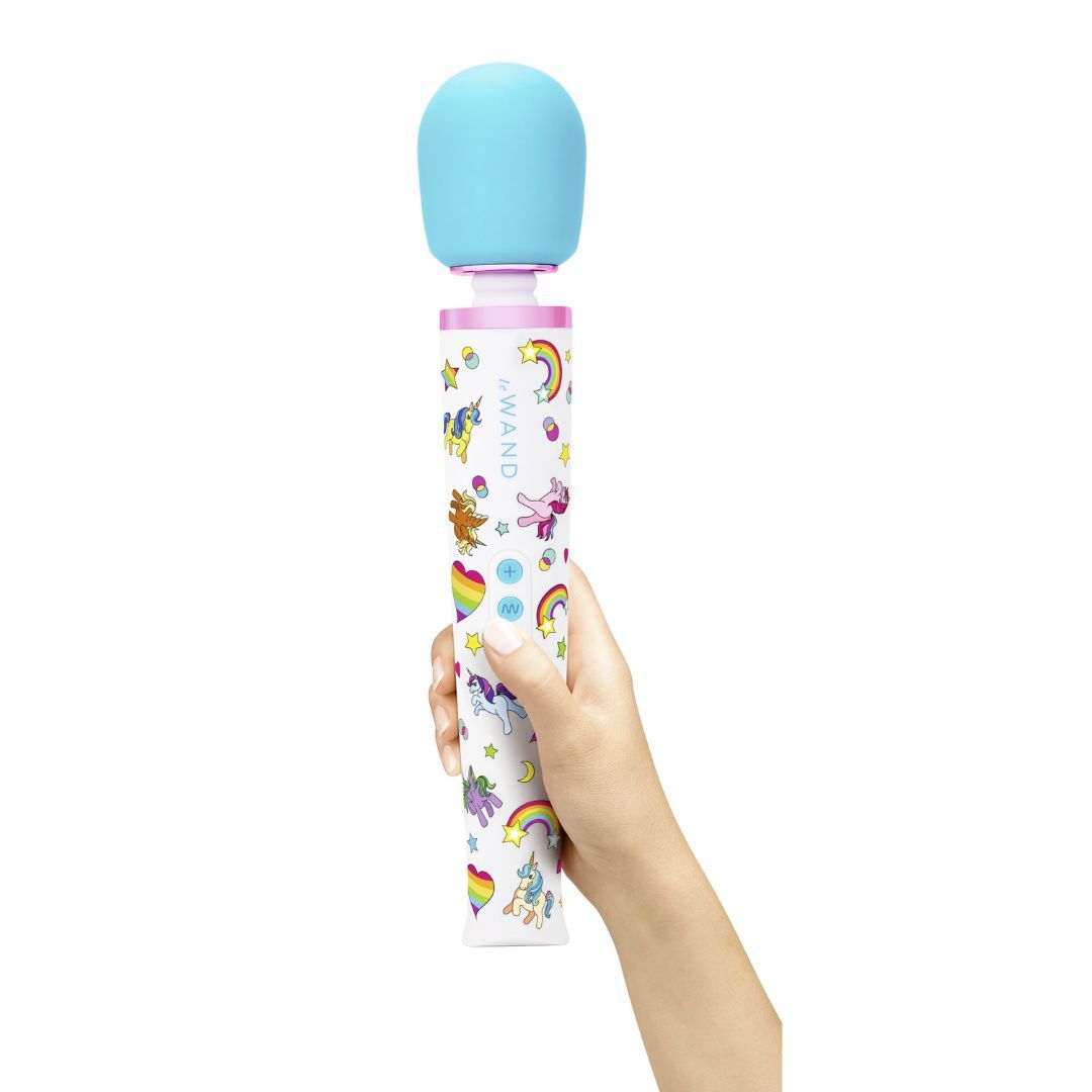 Hand hält le Wand Unicorn Wand. Blauer Massagekopf, weißer Griff mit Einhörnern und Regenbogen. Rosa Akzente.