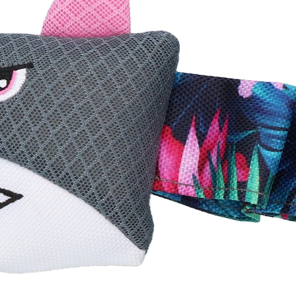 Nahaufnahme eines grauen Spielzeugs mit einem Hai-Design. Der Schwanz hat ein tropisches Muster. Das Spielzeug hat eine rosa Flosse.