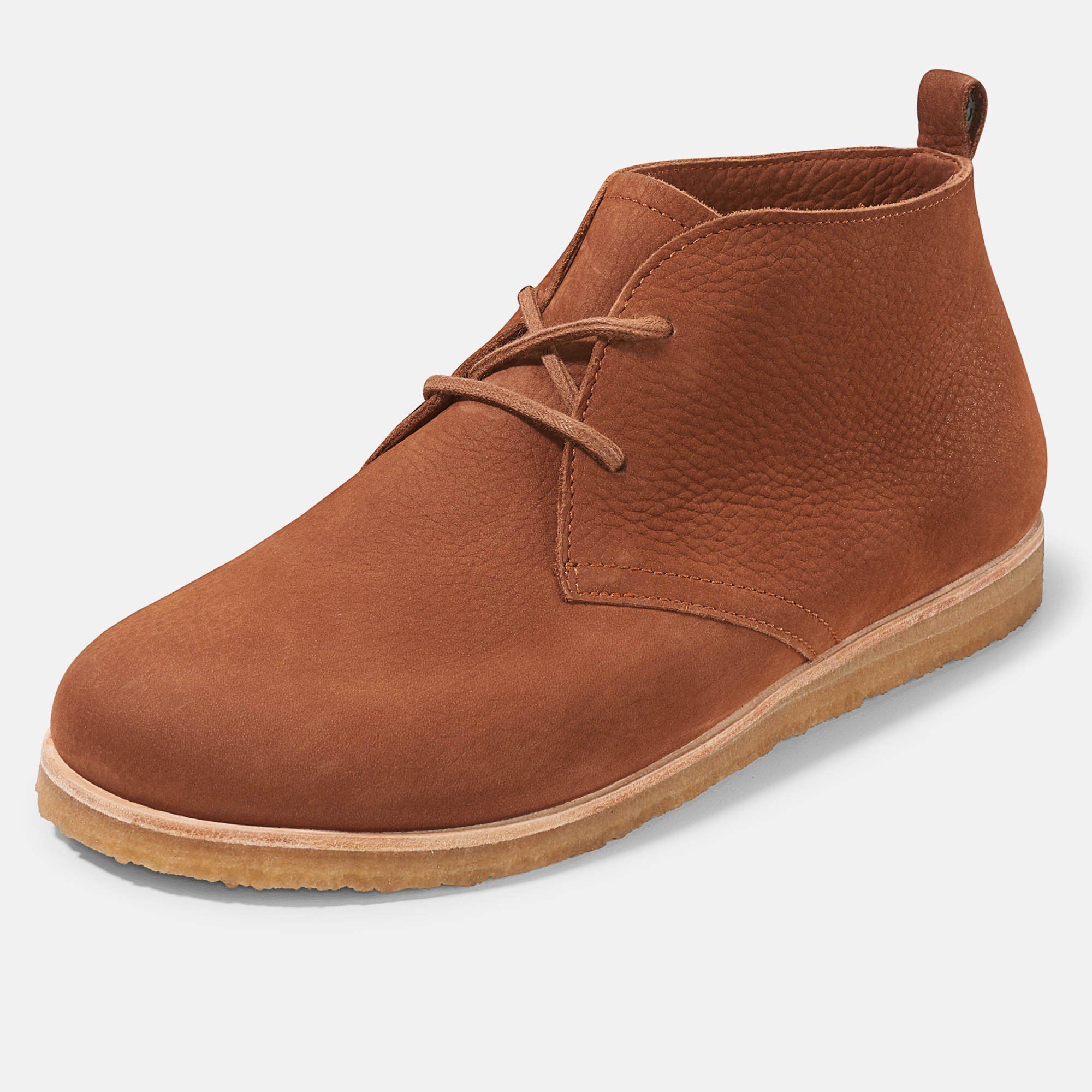 Braune Stiefelette mit Schnürsenkeln. Hellbraune Sohle. Auf hellem Hintergrund.