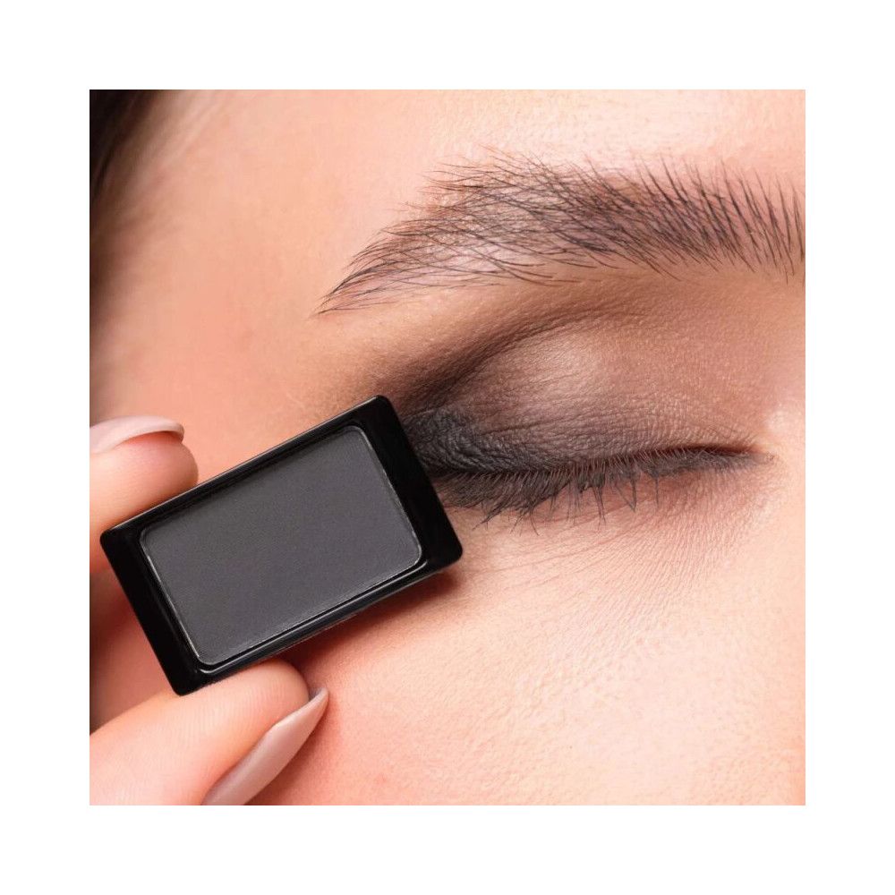 Artdeco Lidschatten 503 Matt Black. Schwarzer Lidschatten wird auf dem Augenlid aufgetragen. Das Produkt wird von einer Hand gehalten.