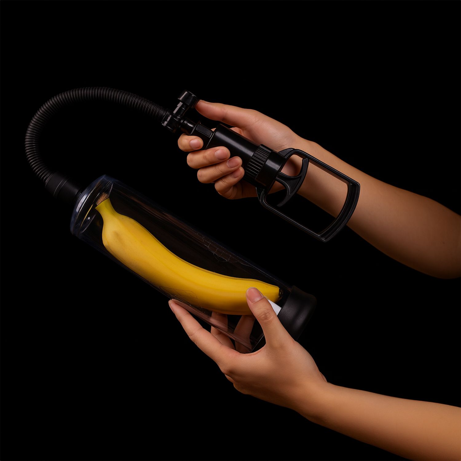 Penispumpe mit Banane im transparenten Zylinder. Hände halten die Pumpe. Schwarzer Griff und flexibler Schlauch.