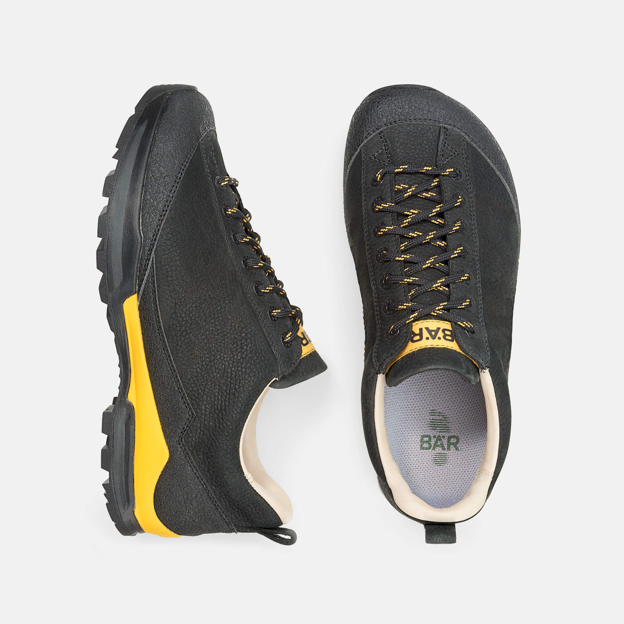 Zwei Wanderschuhe, von oben gesehen. Schwarzes Leder mit gelben Akzenten. Marke BÄR auf der Innensohle.