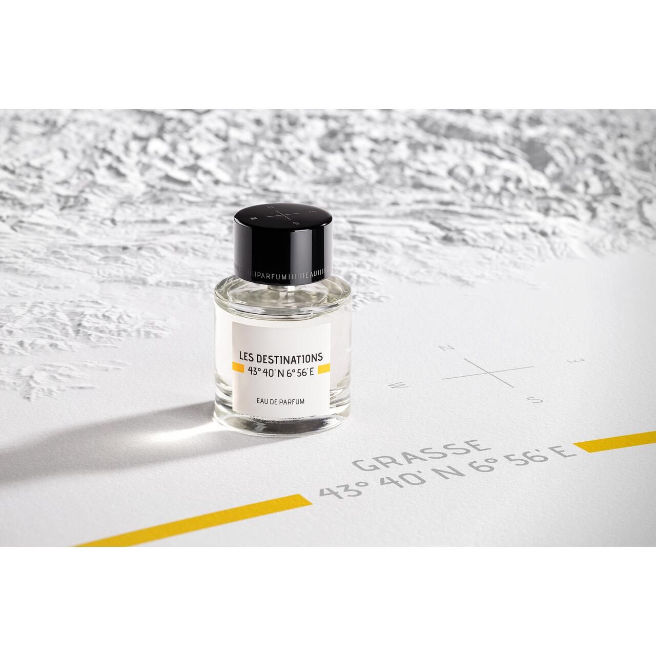 Parfümflakon auf Karte. Aufschrift: Les Destinations, Eau de Parfum. Schwarzer Deckel, transparente Flasche.