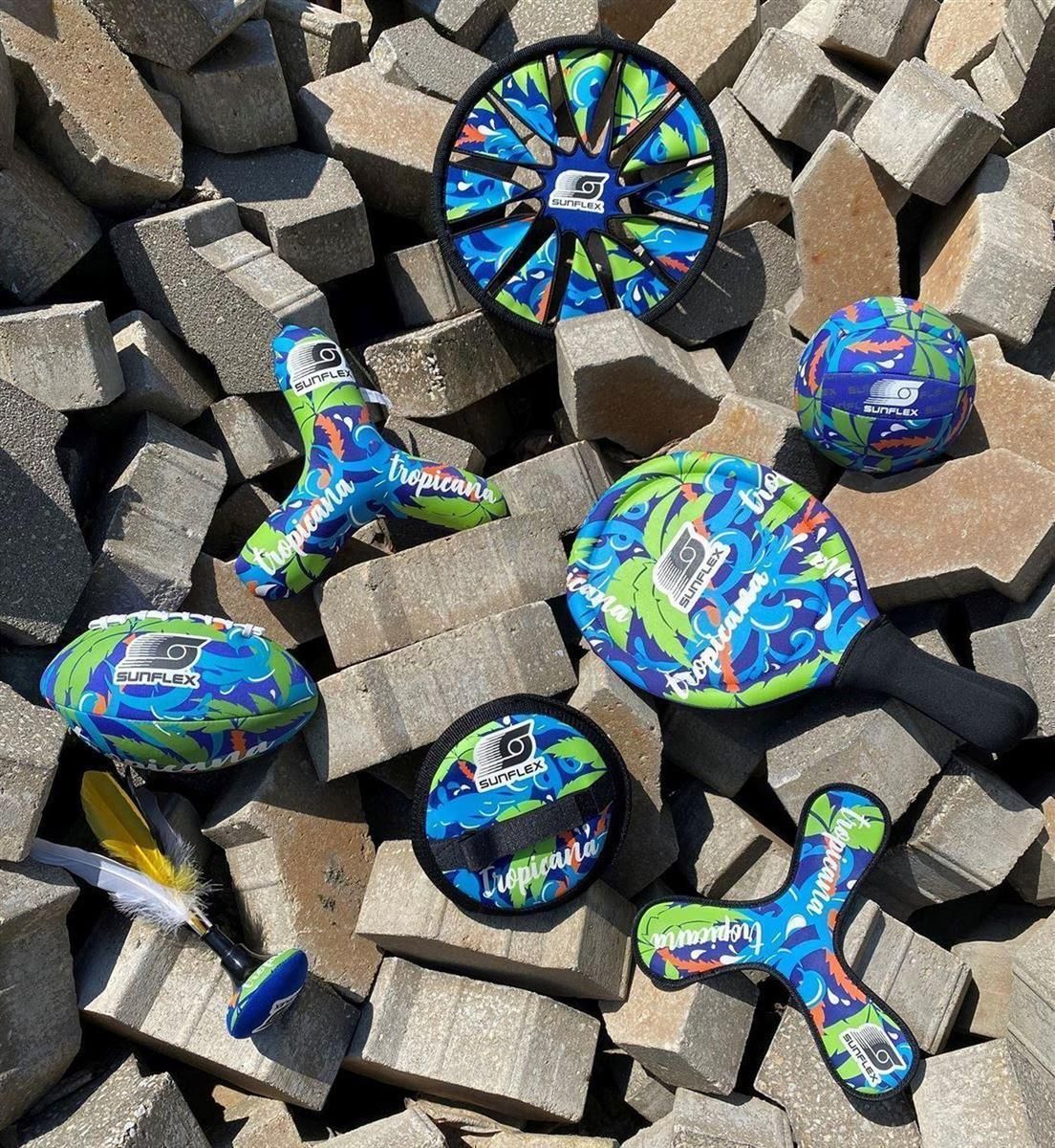 Verschiedene Strandspielzeuge mit tropischem Muster. Darunter Beachball, Frisbee und Boomerang.