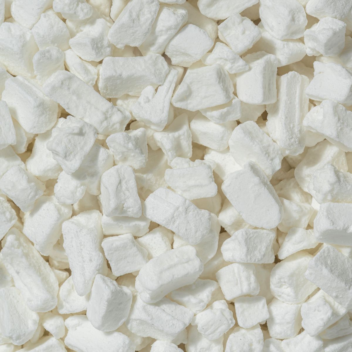 Nahaufnahme von weißen Kokoswürfeln. Viele kleine, unregelmäßig geformte Stücke.
