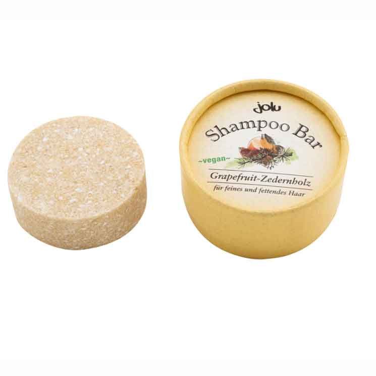 Runder Shampoo Bar und Verpackung. Auf der Verpackung steht "Jolu Shampoo Bar Grapefruit-Zedernholz".